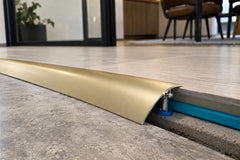 Gold aluminium threshold strip transition between tile and LVT flooring