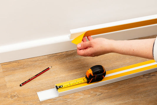 White self-adhesive cable trunking on a skirting board hiding charger cables