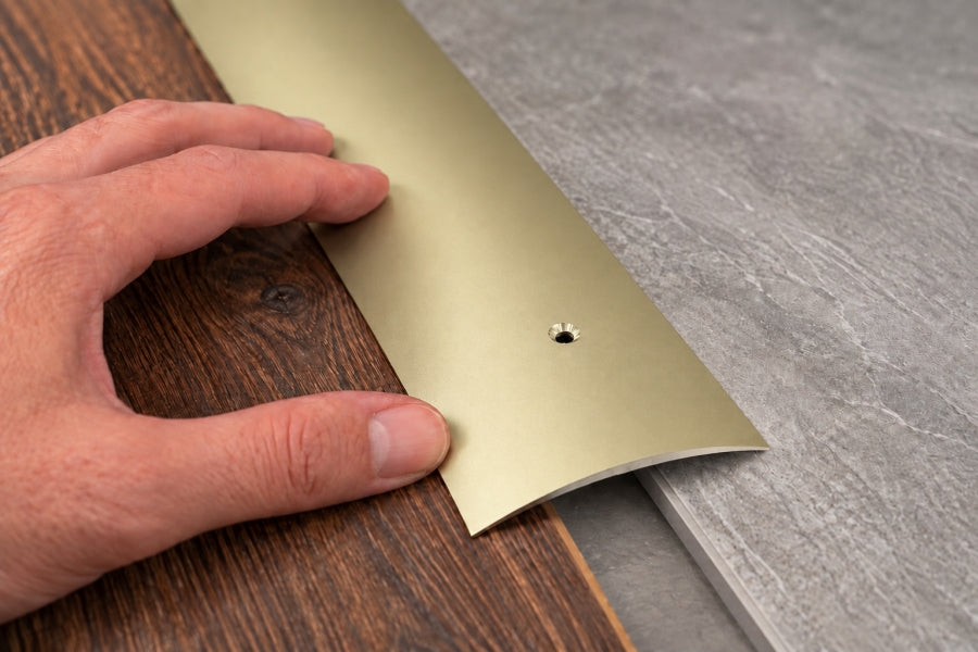 Gold 70mm door threshold strip covering a carpet to laminate transition